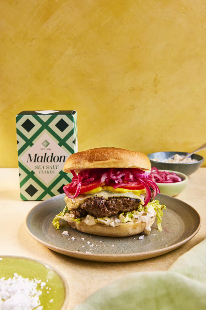 Homemade summer beef burger. Paired with pickled red onions, lettuce, cheese and mustard. Seasoned with Maldon Original Sea Salt 250g pack.