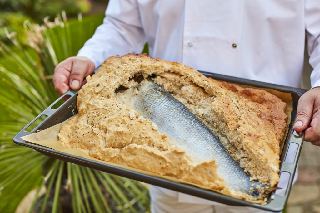 Chef holding tray of salt baked fish