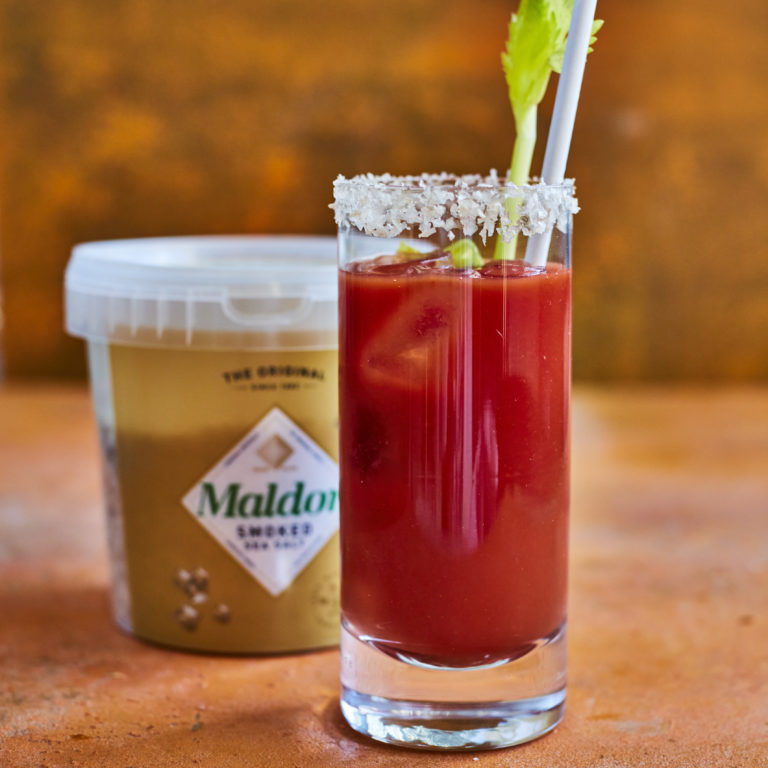 Glass of Bloody Mary cocktail in front of tub of Maldon smoked sea salt