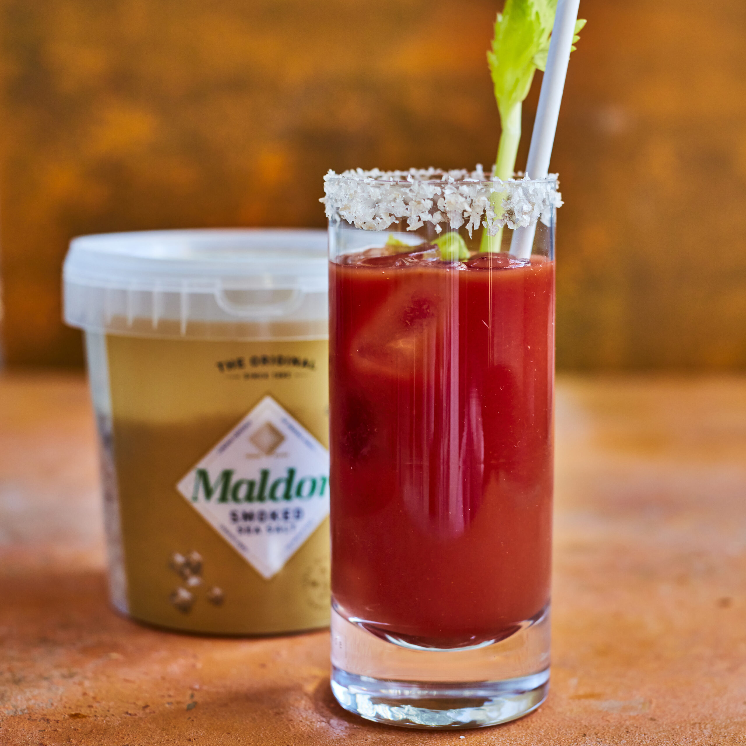 Glass of Bloody Mary cocktail in front of tub of Maldon smoked sea salt
