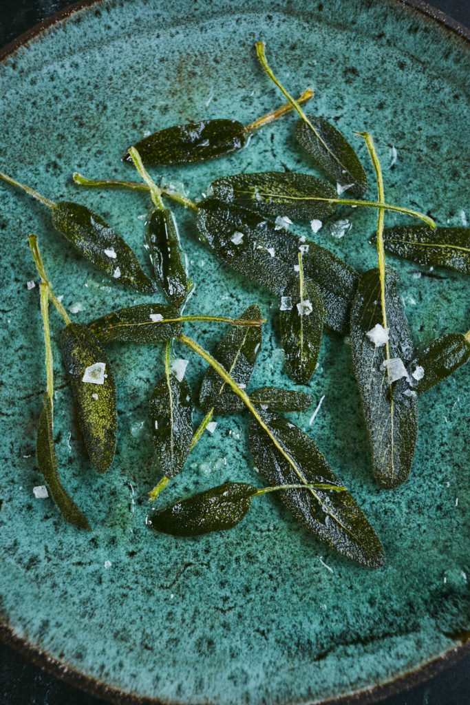 Sage leaves seasoned with sea salt on turquoise plate