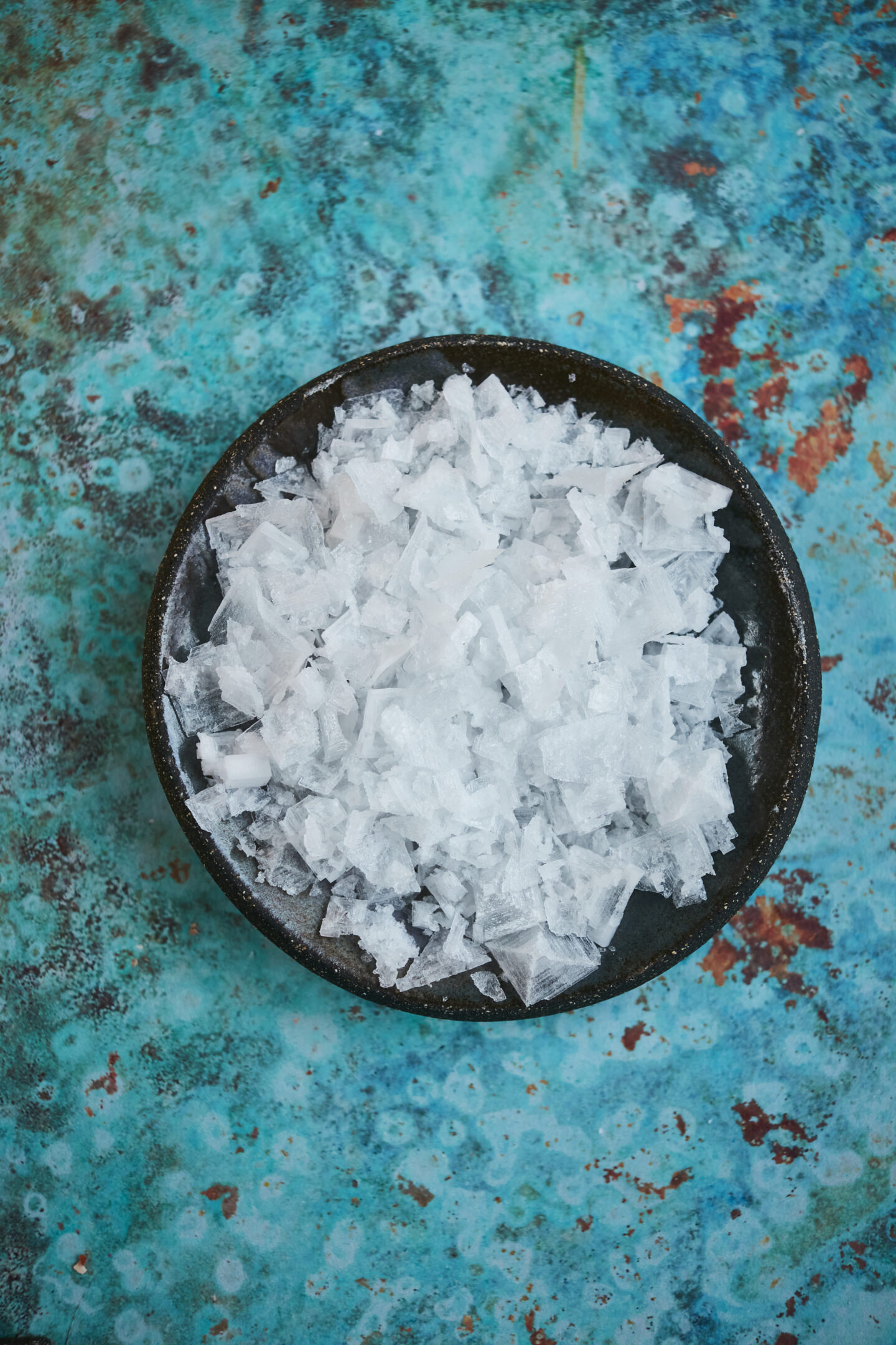 Bowl of sea salt in black bowl on turquoise counter