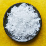 Sea salt in black pot on yellow surface