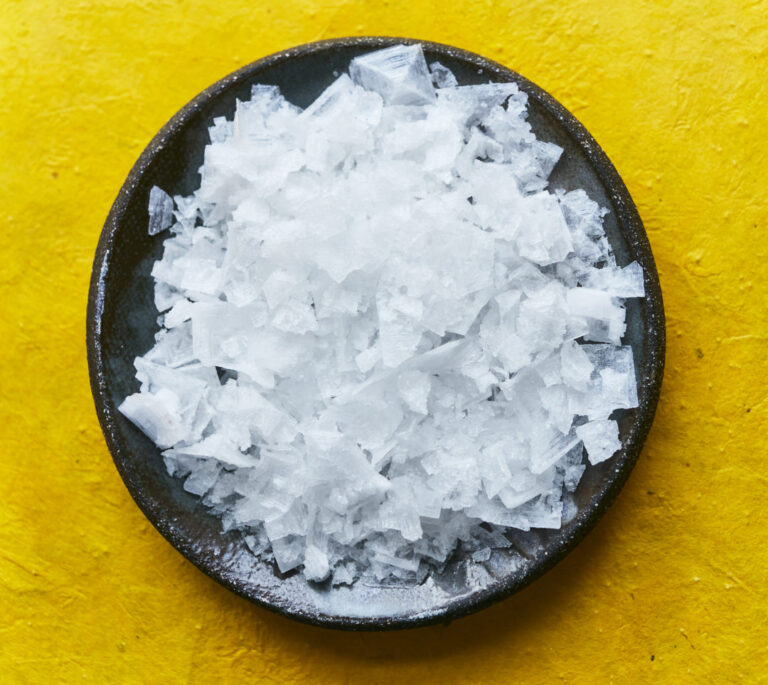 Sea salt in black pot on yellow surface