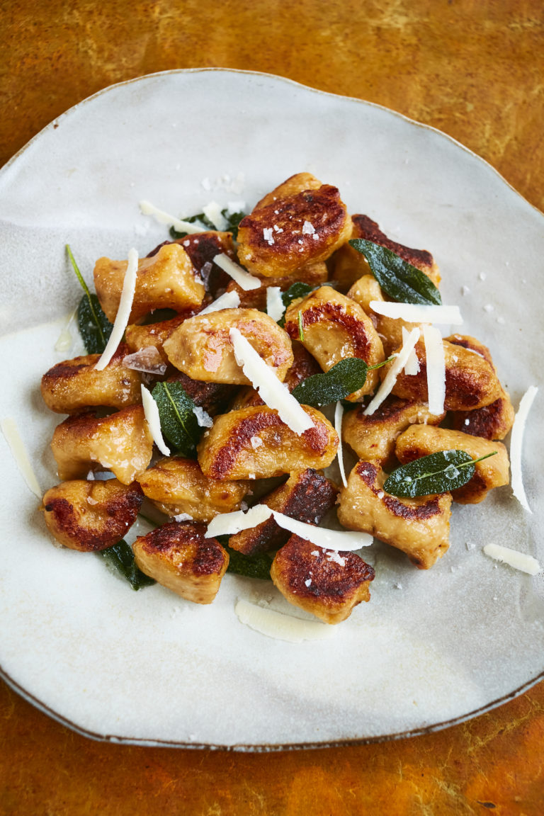 Swede gnocchi on plate with sage leaves and grated parmesan