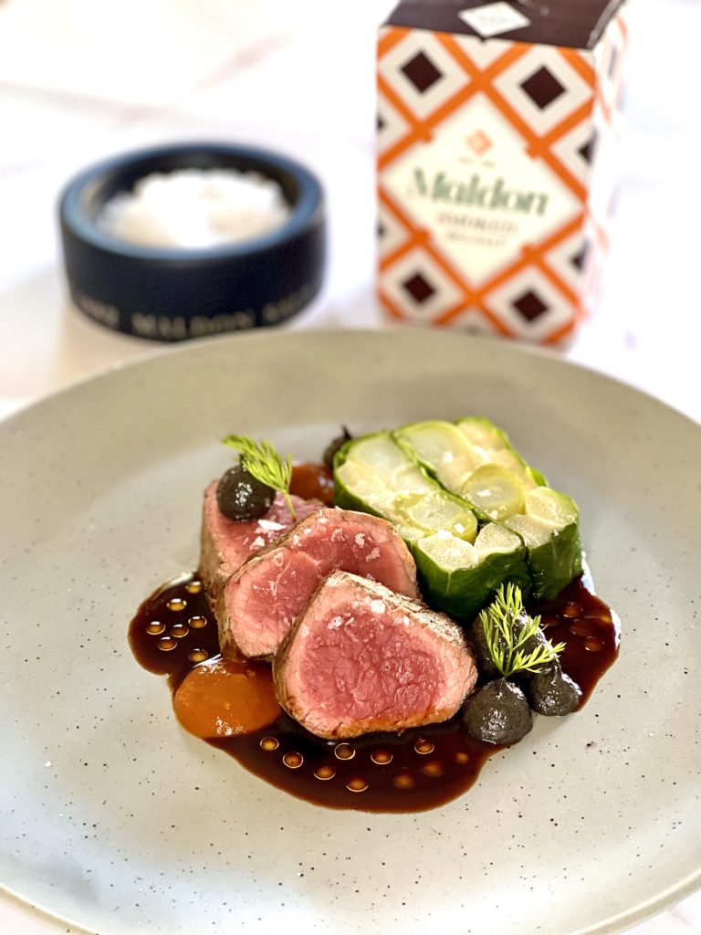 Beef fillet with leek and asparagus terrine served on a plate next to a box of Maldon Salt
