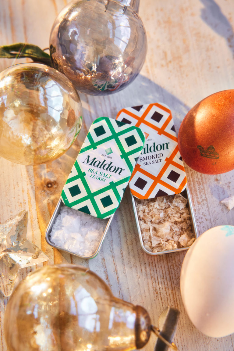 Two Maldon Salt pinch tins, one with classic sea salt and one with smoked sea salt. Clarence Court Eggs sit by the tins.