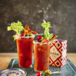 Loaded bloody Mary cocktail. Garnished include prawn tail, cherry tomato, stuffed olive, gherkin and a celery stick. Salt rim made from Maldon Chilli Sea Salt 100g pack.