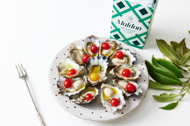 Fermented cherry tomatoes sitting on freshly shucked oysters.