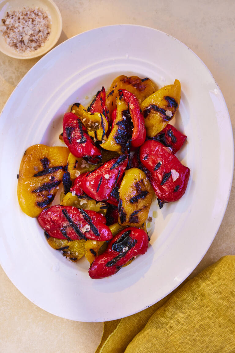 A bowl of smoky grilled red and yellow bell peppers, seasoned with Maldon Smoked Sea Salt.