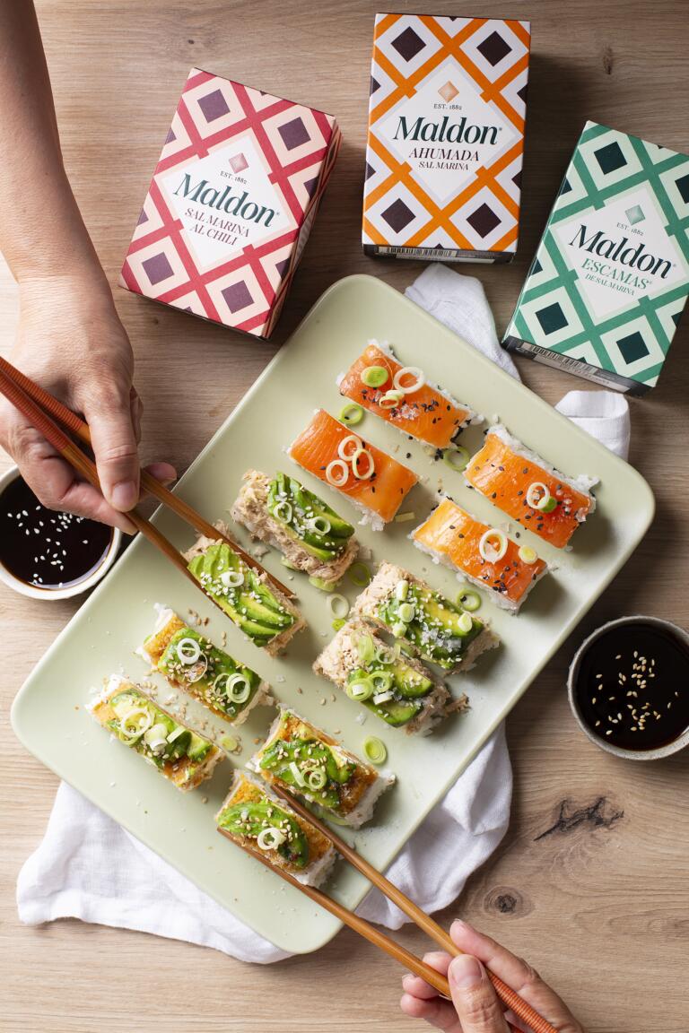 Bandejas de sushi fácil en capas de salmón, atún y aguacate con crispy chicken, cortadas en bocados y terminadas con escamas de Sal Maldon